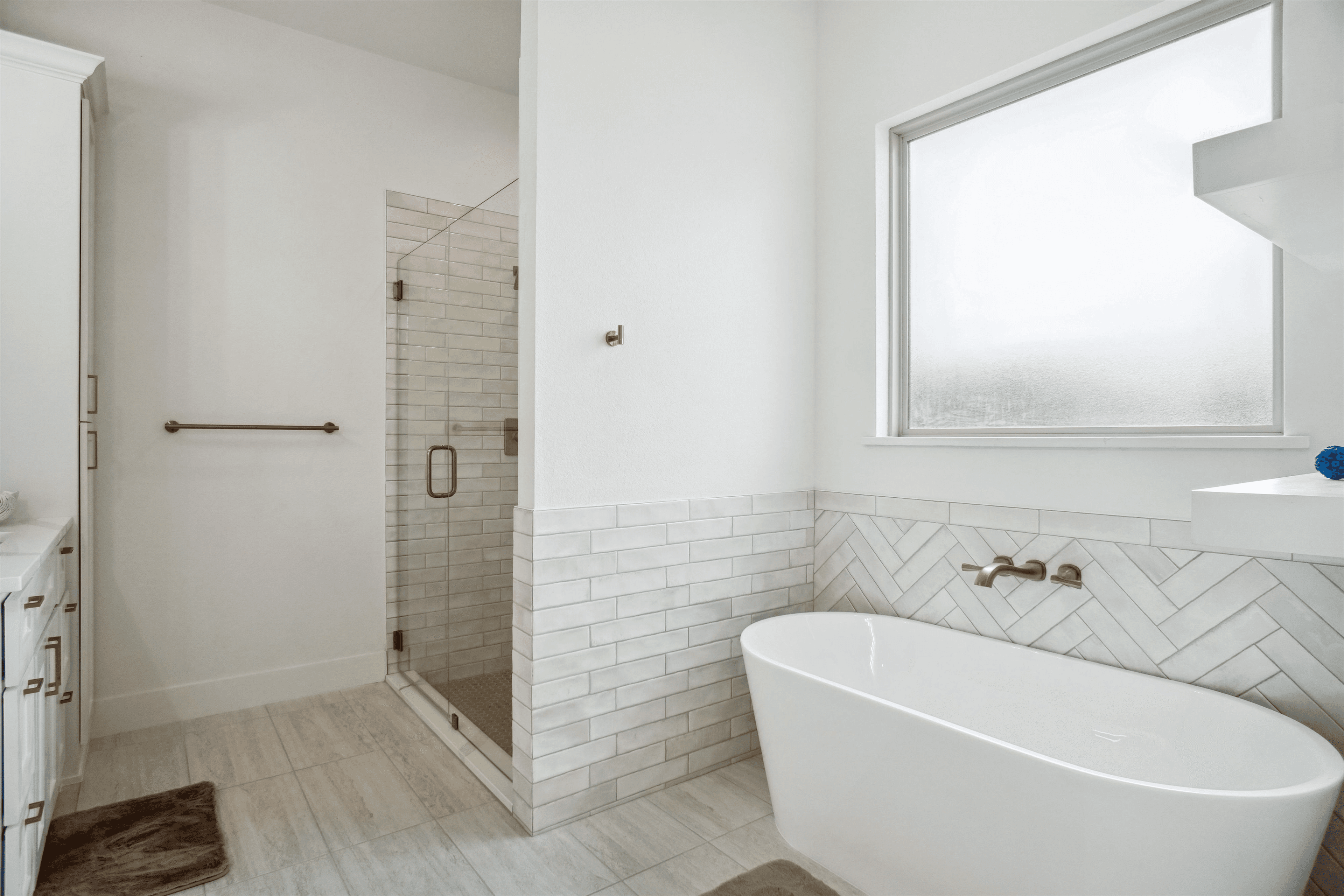 Modern bathroom featuring a white freestanding tub, glass shower, and elegant gold fixtures.