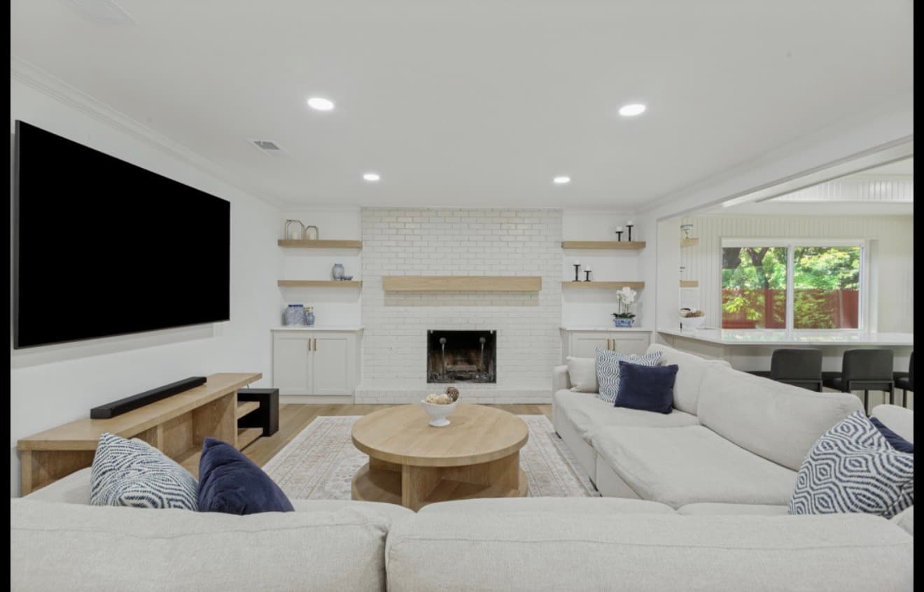 Modern living room with white brick fireplace, large television, and a white sectional sofa.